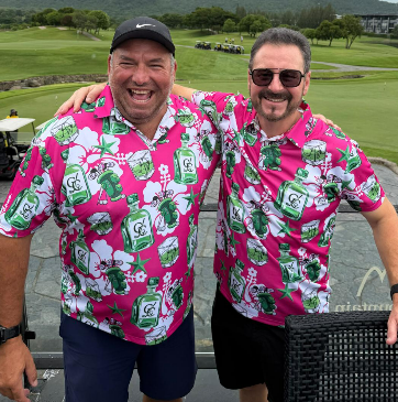 Two CUZZY Golf tour members on the course in matching pink and green whisky bottle print polos